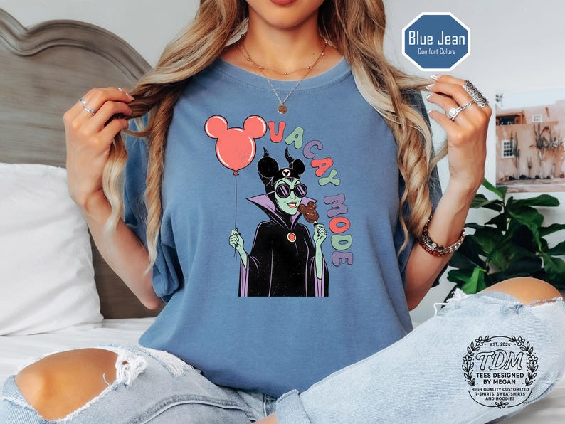 K&ouml;nnte beinhalten: Blaues kurz&auml;rmeliges T-Shirt mit einer Comicfigur, die einen Ballon und Eis h&auml;lt, mit den Worten "VACAY MODE". Das Shirt ist blau und tr&auml;gt den Aufdruck "Blue Jean Comfort Colors".