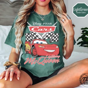 Puede incluir: Camiseta verde claro con un gr&aacute;fico de Rayo McQueen de Cars de Disney Pixar. El dise&ntilde;o incluye el logotipo de Cars, una bandera a cuadros y el texto "Lightning McQueen". La camiseta tambi&eacute;n tiene el texto "LightGreen Comfort Colors".