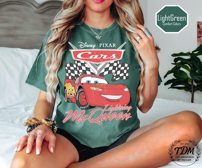 Puede incluir: Camiseta verde claro con un gr&aacute;fico de Rayo McQueen de Cars de Disney Pixar. El dise&ntilde;o incluye el logotipo de Cars, una bandera a cuadros y el texto "Lightning McQueen". La camiseta tambi&eacute;n tiene el texto "LightGreen Comfort Colors".