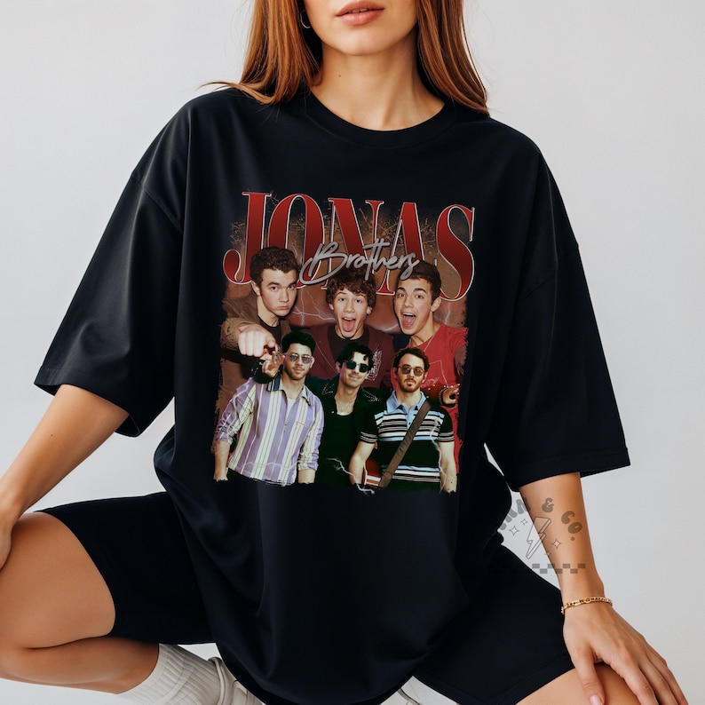 May include: A black oversized t-shirt featuring a graphic print of the Jonas Brothers. The design includes the text JONAS in large red letters and Brothers in script, with a collage of the band members in various outfits and poses.