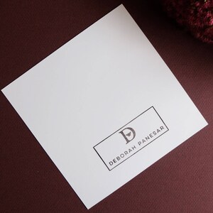 May include: A white card with a black rectangle containing the letter "D" and the text "DEBORAH PANESAR".