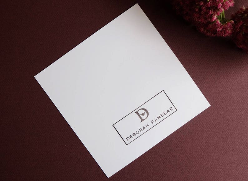 May include: A white card with a black rectangle containing the letter "D" and the text "DEBORAH PANESAR".