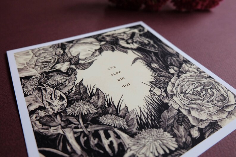 May include: Black and white illustration of flowers and foliage with the text "Live Slow Die Old" in the centre.