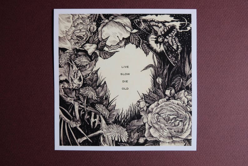 May include: Black and white illustration of flowers, leaves, and a butterfly with the text "Live Slow Die Old" printed in the centre.