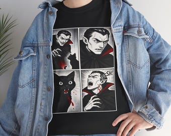 May include: Black t-shirt featuring a comic strip design with vampire illustrations and a black cat. The panels depict a vampire with a red-lined cape and the cat with blood. The word "HSSSH!" is in a speech bubble.