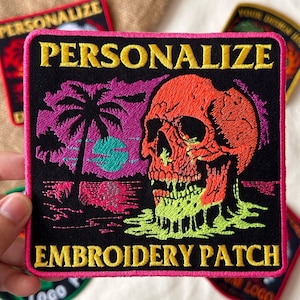 May include: Embroidered patch with a black background, featuring a skull, palm tree, and the words "PERSONALIZE EMBROIDERY PATCH" in yellow and pink. The skull is orange and green, and the palm tree is purple.