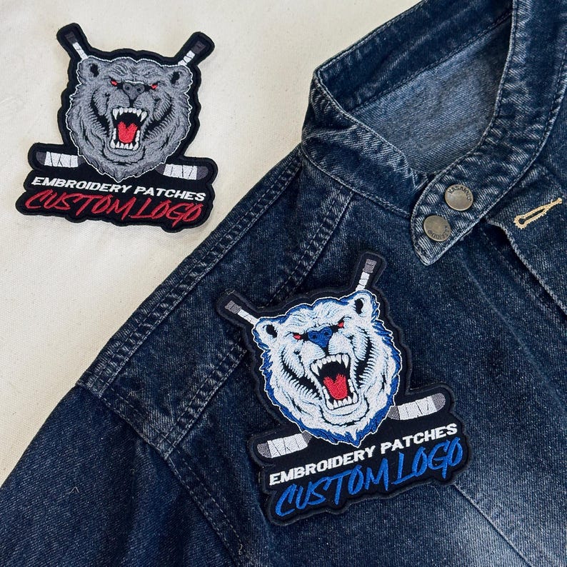 May include: Embroidered patches featuring a snarling bear with hockey sticks. The patches have the text "EMBROIDERY PATCHES CUSTOM LOGO" in white and red. One patch is on a denim jacket.