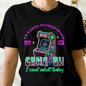 May include: Black t-shirt with a colorful arcade game graphic. The design includes the text "I'm a Level 99 Couch Potato" and "Game On! I can't adult today."