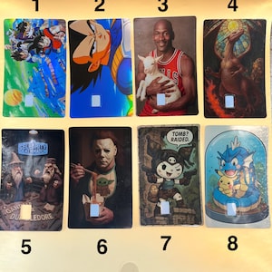 May include: A set of eight rectangular cards with diverse images. The collection includes anime characters, Michael Jordan with a goat, a dragon, and characters from Celebrity Deathmatch. Each card has a small square at the bottom.