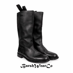 May include: A pair of tall, black leather boots with a pull tab at the top. The boots have a smooth finish and a low heel. The brand name "BarshWearCo" is printed at the bottom of the image.