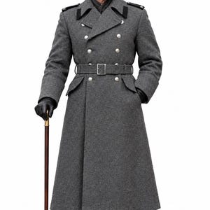 May include: A long, double-breasted grey wool overcoat featuring silver-toned buttons, black collar tabs, and a matching waist belt. The ensemble includes a grey peaked cap, black leather gloves, black leather boots, and a wooden walking cane.