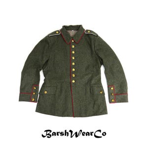 May include: An olive green military-style jacket with red trim and gold buttons. The jacket has a collar, two front pockets, and white shoulder accents. The text "BarshWearCo" is at the bottom.
