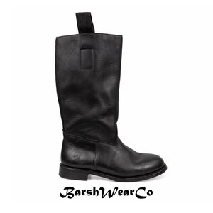 May include: A black leather knee-high boot with a pull tab at the top. The boot has a rounded toe and a low heel. The brand name "BarshWearCo" is printed at the bottom of the image.