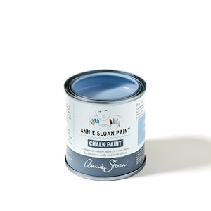 Könnte beinhalten: Eine kleine, offene Dose Annie Sloan Kreidefarbe in Hellblau. Die Dose hat einen silbernen Rand und ein Etikett mit dem Markennamen und Produktdetails. Das Etikett zeigt auch eine Zeichnung einer Person.