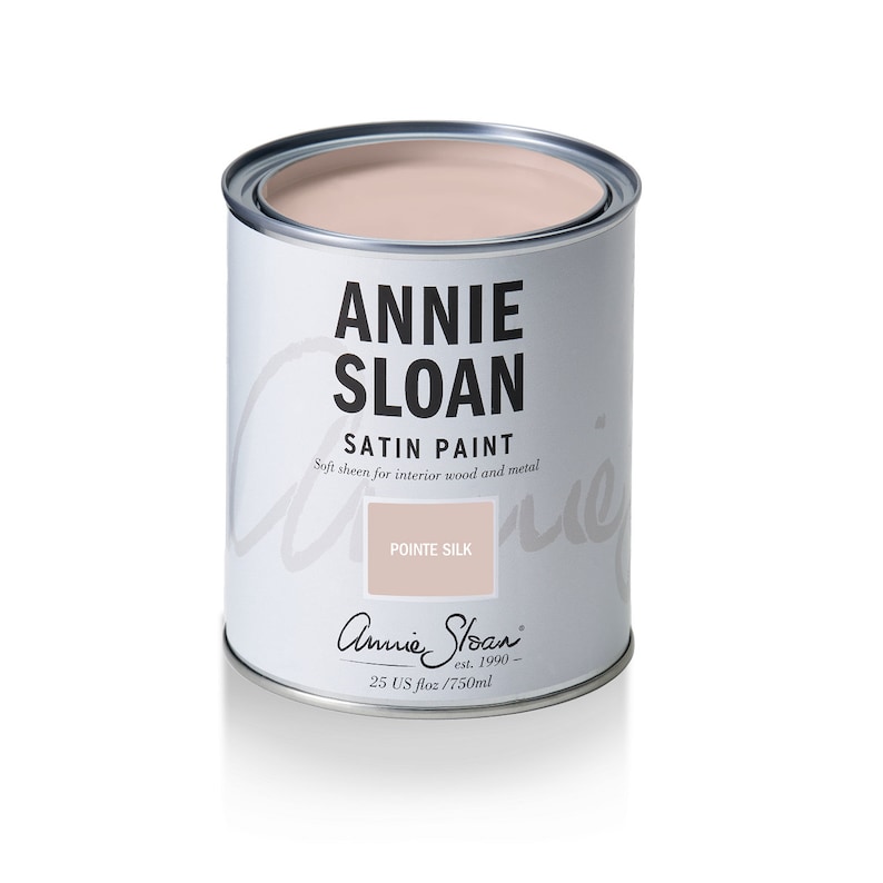 May include: A can of Annie Sloan Satin Paint in the color Pointe Silk. The can is white with black lettering and a pink lid. The paint is for interior wood and metal and is 25 US fl oz / 750 ml.