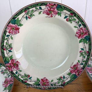 May include: A white ceramic soup bowl with a green and black floral border. The border features pink flowers and green leaves. The bowl is in good condition with no chips or cracks.
