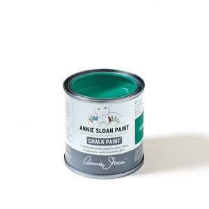 May include: A small tin of Annie Sloan Chalk Paint, filled with teal-colored paint. The tin has a silver body with white and green labels, displaying the brand name and product information. The paint is for furniture, walls, and paint effects.