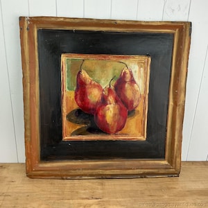 May include: A square framed oil painting depicting three red pears on a yellow and green background. The artwork is encased in a wide, distressed gold and brown wooden frame with a black inner border, featuring a visible artist signature.