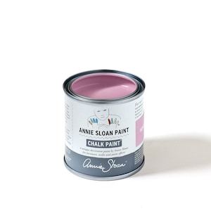 Könnte beinhalten: Eine Dose Annie Sloan Chalk Paint in der Farbe French Linen. Die Dose ist silberfarben mit einem weißen Etikett und zeigt eine Comic-Illustration einer Person mit bunten Händen. Der Text auf dem Etikett lautet "Annie Sloan Paint Chalk Paint a unique decorative paint by Annie Sloan for furniture, walls and paint effects Annie Sloan".
