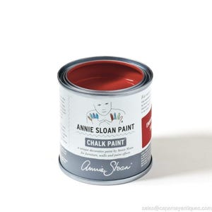 May include: A small, open can of Annie Sloan Chalk Paint in a vibrant red hue. The can is silver with a white label featuring the brand name and the words "Chalk Paint." The label also includes the text "a unique decorative paint by Annie Sloan for furniture, walls and paint effects."