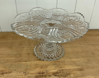 Soporte para pasteles de vidrio prensado vintage con borde festoneado y diseño floral en forma de estrella.