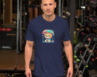 May include: Navy blue short-sleeve t-shirt featuring a cartoon lion under a colorful umbrella in the rain. The lion is light brown with a yellow mane and is sitting in the rain. The umbrella has red, yellow, green, and blue colors.