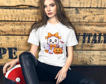 Può includere: T-shirt bianca con un personaggio di un fantasma dei cartoni animati con un fiocco arancione, che tiene in mano una zucca e delle caramelle. Il fantasma indossa un lenzuolo viola. La maglietta è a girocollo e maniche corte.