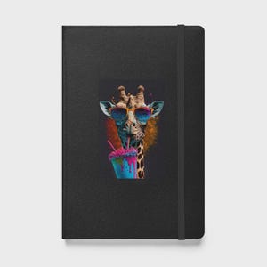 May include: Black notebook with a colorful illustration of a giraffe wearing sunglasses and holding a blue drink with pink and purple toppings. The giraffe is set against a black background.
