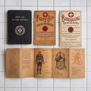 May include: A selection of antique first aid manuals and anatomical diagrams. The image features a black book, "First Aid to the Injured", and several pamphlets with illustrations and instructions. The color scheme is predominantly black, white, and sepia.