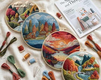 May include: Four circular embroidery hoops featuring landscape scenes of mountains, forests, and water, accompanied by colorful embroidery floss skeins, needles, and a magazine titled The Needle and Thread Review on a white fabric background.