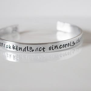 May include: Silver bracelet with the inscription "Speak kindly, act sincerely, choose love."