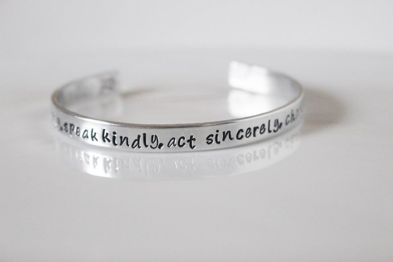 May include: Silver bracelet with the inscription "Speak kindly, act sincerely, choose love."