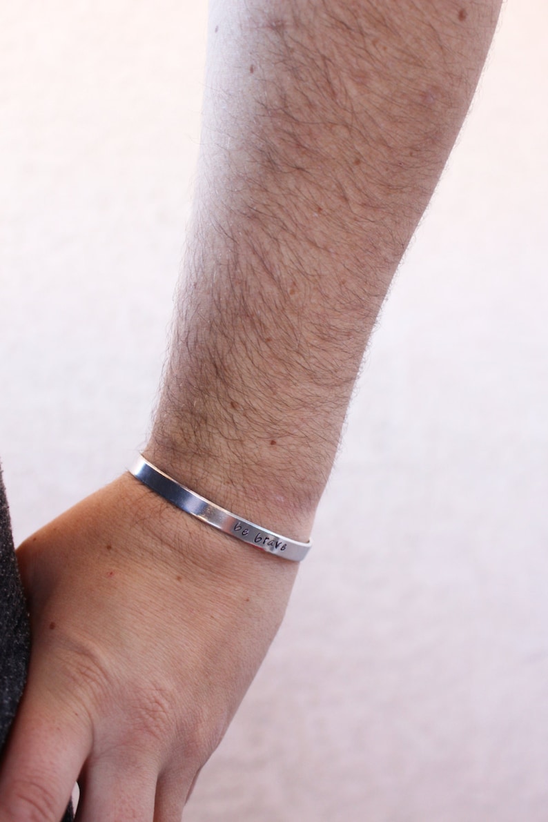 May include: A silver bracelet with the words "Be Brave" engraved on it.