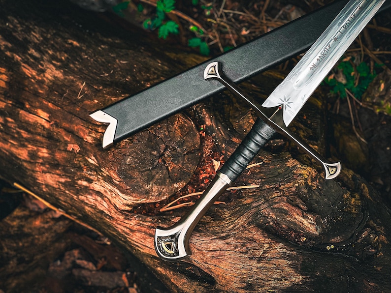 May include: A detailed image of a sword with a silver blade and a black handle, resting on a weathered wooden surface. The sword has a decorative hilt and a black sheath. The blade has an inscription and a star design.