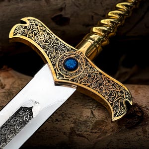 May include: Close-up of an ornate sword with a gold-colored hilt and a silver blade. The hilt features intricate black and gold filigree designs and a blue gemstone. The blade has a detailed pattern. The sword is a decorative item.