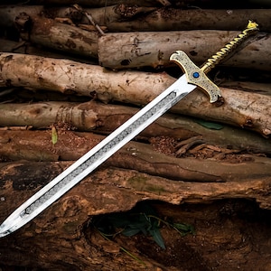 May include: A decorative sword with a silver blade and a gold-colored hilt. The hilt features intricate designs and a blue gem. The sword is resting on a pile of wooden logs, creating a rustic and fantasy-themed aesthetic.