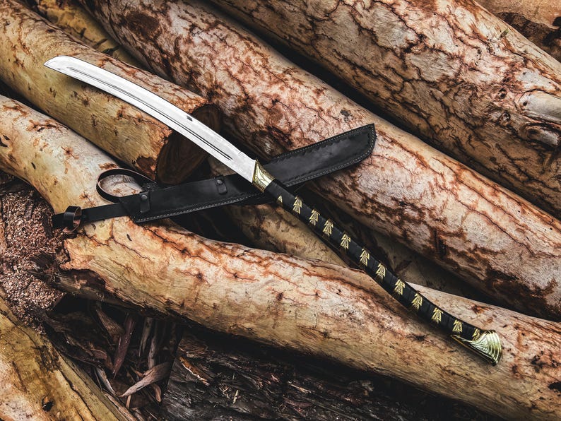 K&ouml;nnte beinhalten: Ein Katana-Schwert mit gebogener Klinge, schwarzem Griff und goldenen Akzenten, das auf einem Stapel Holzst&auml;mme liegt. Das Schwert befindet sich in einer schwarzen Lederscheide. Der Griff hat ein dekoratives Muster.