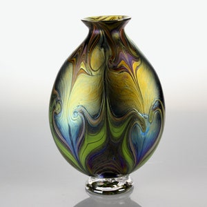May include: A round glass vase with a swirling pattern of green, blue, and gold. The vase has a clear glass base.