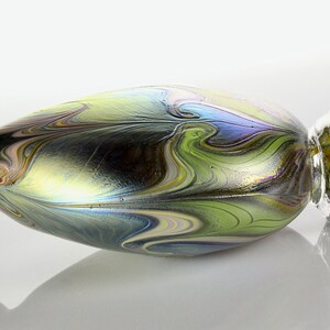 May include: A small, iridescent glass vase with a swirling pattern of green, blue, and gold. The vase has a rounded body and a narrow neck.