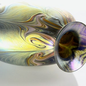 May include: A glass vase with a swirling pattern of gold, brown, and purple iridescent glass. The vase has a wide mouth and a narrow neck.