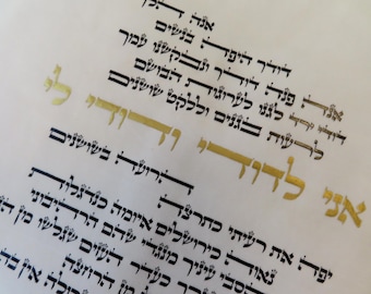 May include: Close-up of a page with Hebrew calligraphy in black ink. Some words are highlighted in gold. The text is arranged in vertical lines, with a few words in larger, stylized fonts.