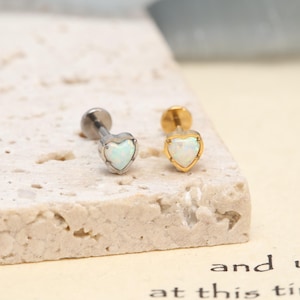 Peut inclure: Deux boucles d'oreilles à dos plat avec des pierres d'opale blanche en forme de cœur. L'une possède une monture en métal argenté, l'autre une monture en métal doré. Chaque boucle est dotée d'une tige et d'un embout circulaire plat.