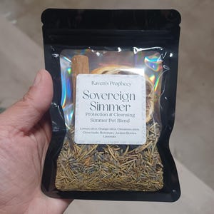 Può includere: Un sacchetto nero contenente una miscela per pentola a fuoco lento. L'etichetta recita "Raven's Prophecy Sovereign Simmer Protection & Cleansing Simmer Pot Blend". Gli ingredienti includono fette di limone e arancia, stecca di cannella, chiodi di garofano, rosmarino, bacche di ginepro e lavanda.