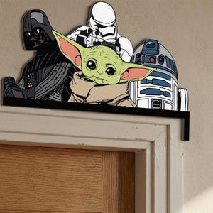 May include: A black shelf featuring Star Wars characters Darth Vader, a Stormtrooper, Grogu (Baby Yoda), and R2-D2. The shelf is mounted above a wooden door frame. The characters are in a cartoon style.