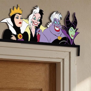 Pode incluir: Um adorno decorativo para portas com quatro vil&otilde;es de desenhos animados: a Rainha M&aacute;, Cruella de Vil, Ursula e Mal&eacute;fica. As figuras s&atilde;o em cores vibrantes e s&atilde;o montadas numa prateleira preta, projetada para ser colocada acima de uma moldura de porta.
