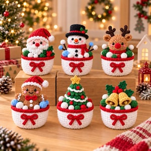 May include: Six crocheted Christmas ornaments in white bowls with red bows. The figures include Santa Claus, a snowman, a reindeer, a gingerbread person, a decorated Christmas tree, and two gold bells with green holly leaves and red berries.