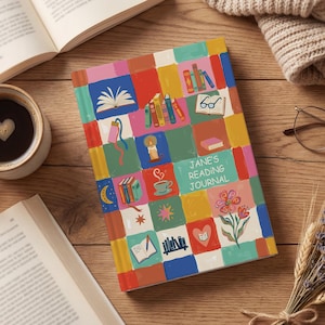 Op de afbeelding: Een kleurrijk leesdagboek met een patchwork ontwerp met illustraties gerelateerd aan boeken. Het dagboek, getiteld "Jane's Reading Journal", ligt op een houten oppervlak met open boeken, een kopje koffie, een bril en een bosje lavendel.