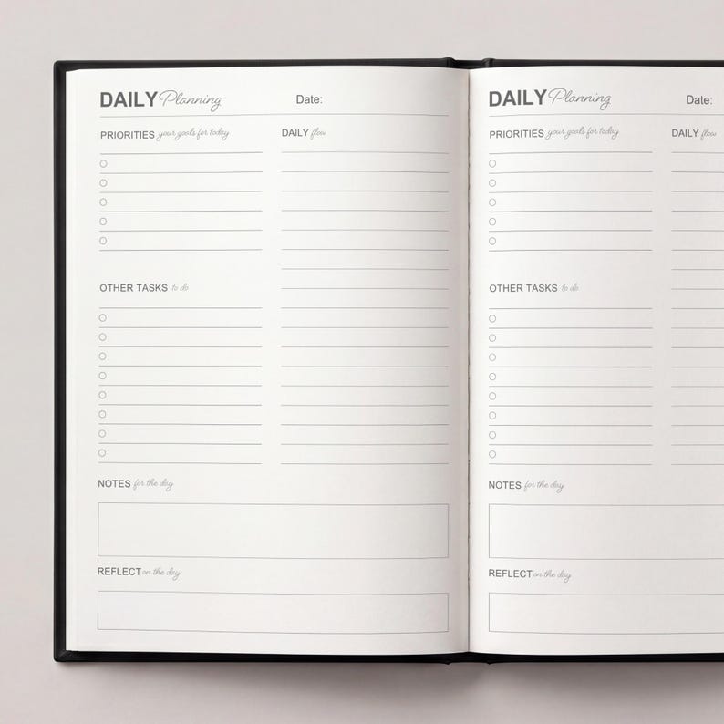 May include: Open black notebook with the words "DAILY Planning" at the top of each page. The pages are lined with sections for priorities, tasks, notes, and reflection. The notebook is open, displaying two facing pages.