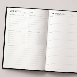 May include: Open black notebook with a weekly planning layout. The left page includes sections for priorities, other tasks, reminders, and notes. The right page is for daily scheduling, with spaces for each day of the week.