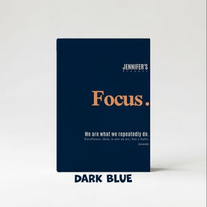 May include: A dark blue planner with the text "JENNIFER'S Planner" at the top. The word "Focus" is in large orange letters. Below, it reads "We are what we repeatedly do. Excellence, then, is not an act, but a habit. Aristotle." The bottom reads "DARK BLUE."